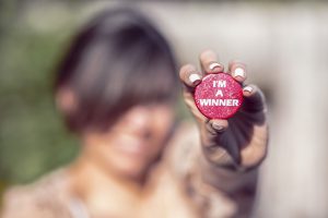 Woman holding "I'm a Winner" pin, showing why you should define success for your dealer email marketing