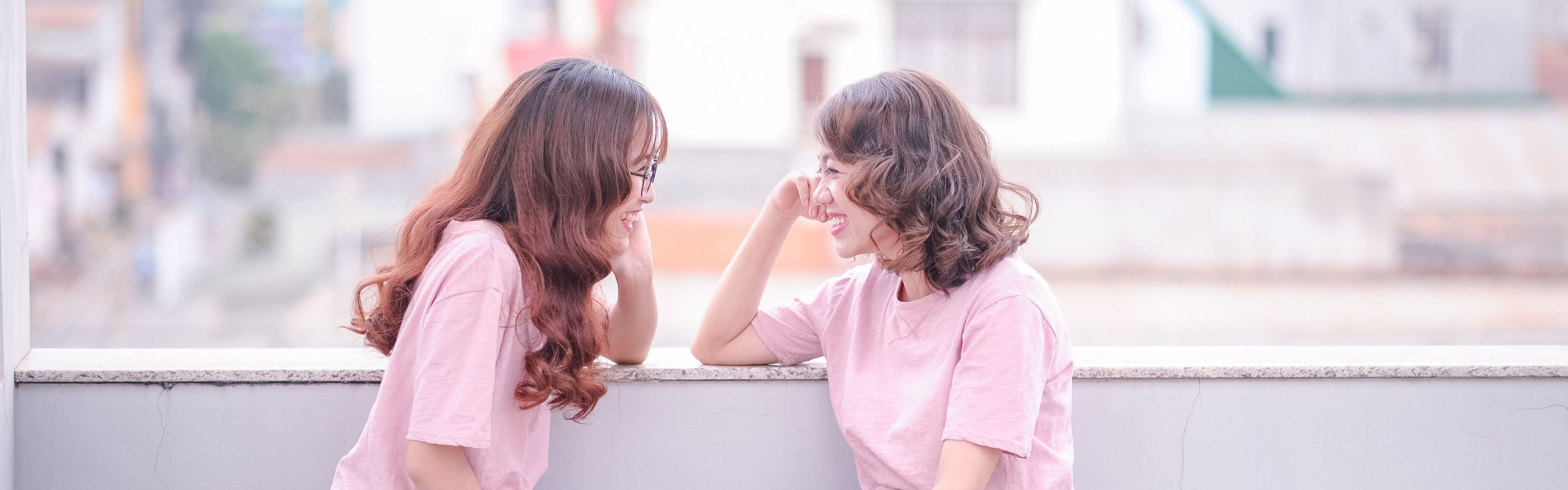 Two similar girls in pink shirts laughing at each other, illustrating testing only one variable in Facebook ads