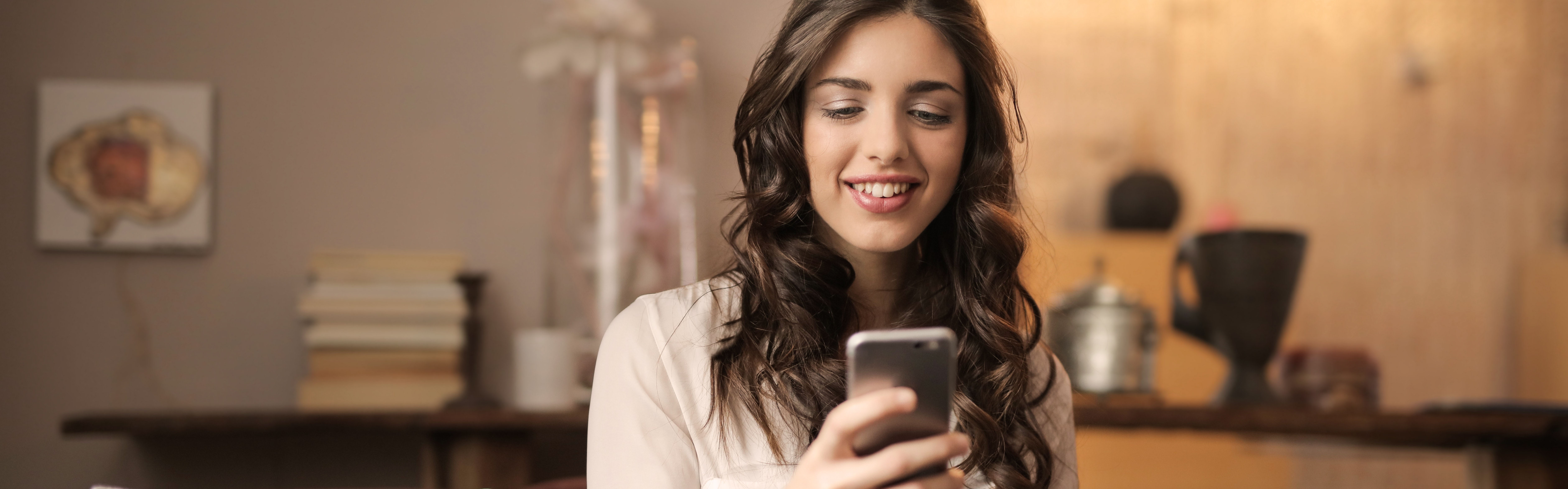 Young woman smiling at smartphone, possibly checking her email metrics.