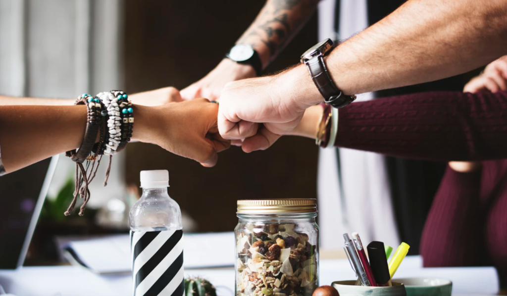 Five people fist bumping, showing why you should develop SMART goals as a team