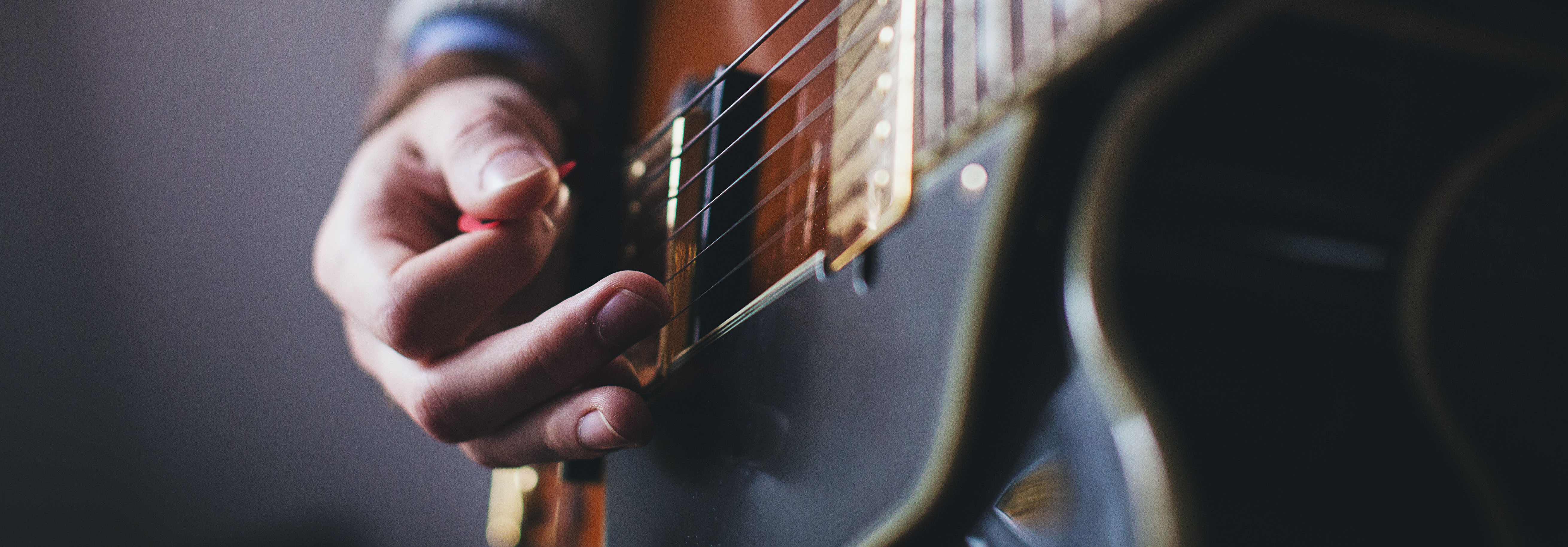 Someone playing the guitar, tightly focused on the fingers. If the instrument fits, play it. 
