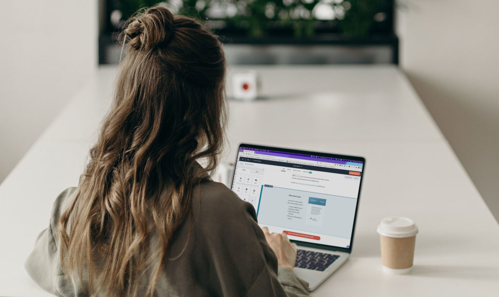 woman sitting at a table building a marketing email on her computer in hubspot