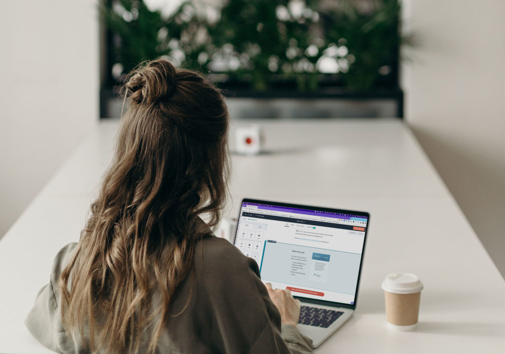 woman sitting at a table building a marketing email in Hubspot