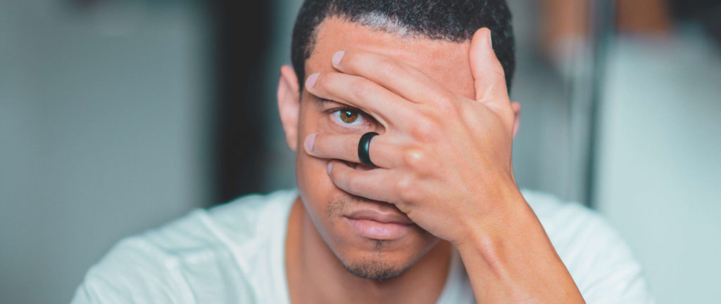 man covering face, avoiding negative topics about his auto dealership