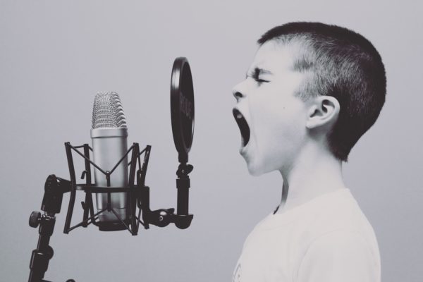 Boy shouting into a microphone, illustrating content promotion strategies
