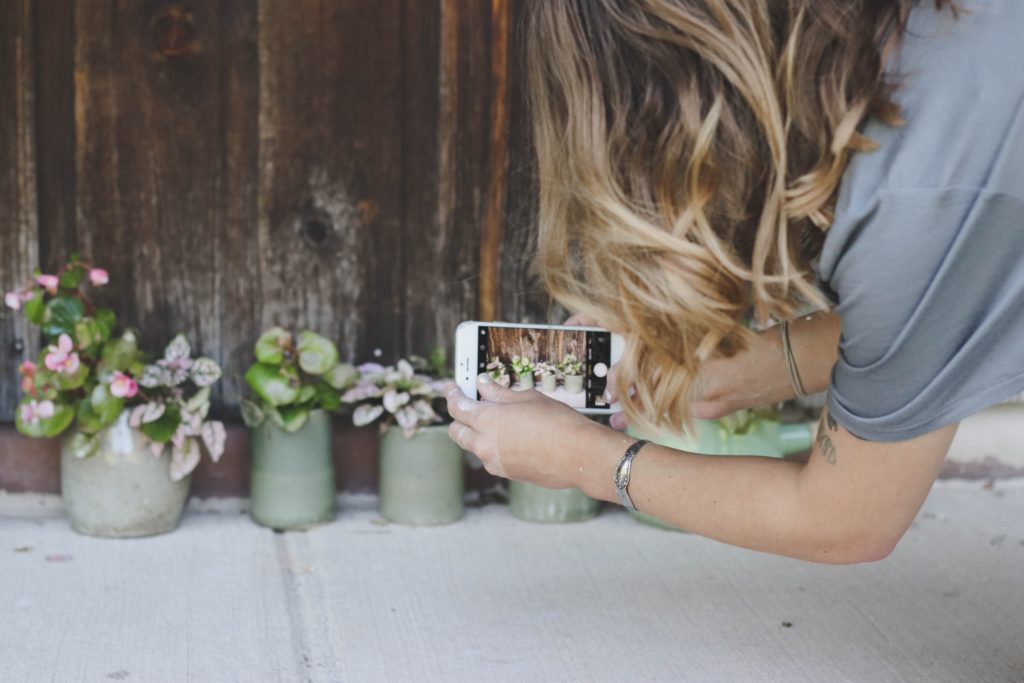 Woman taking a picture of potted plants with her phone