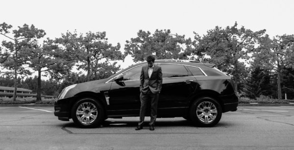 A man in a suit standing by his car.